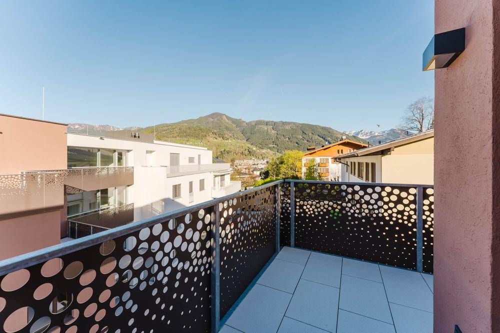 Moderner Balkon mit perforierter Brüstung und Panoramablick auf die Berge und die umliegende Bebauung.