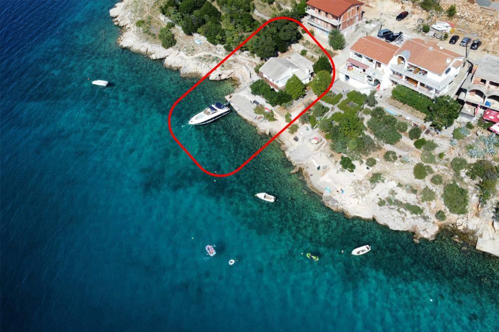 Luftaufnahme eines Anwesens direkt am Meer mit Bootsanleger und üppiger Vegetation.