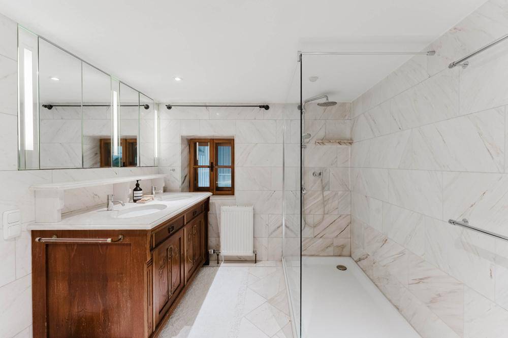 Modernes Badezimmer mit Doppelwaschbecken, großer begehbarer Dusche und Marmorfliesen.