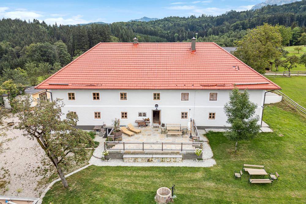 Die Hauptfassade des Anwesens mit einer einladenden Terrasse, ausgestattet mit Liegestühlen und Sitzgelegenheiten.