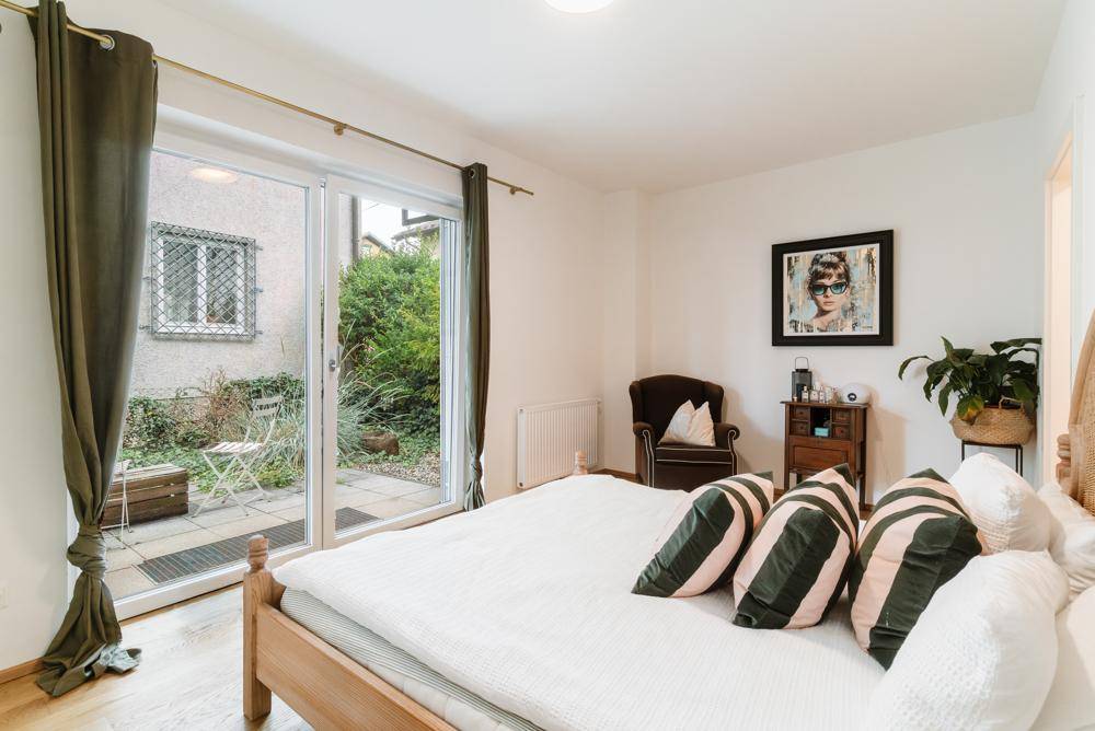 Gemütliches Schlafzimmer mit Holzbett, Parkettboden und direktem Zugang zu einer kleinen Terrasse.