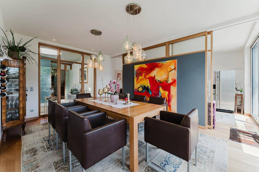 Eleganter Essbereich mit Holztisch, bequemen Stühlen und moderner Beleuchtung.