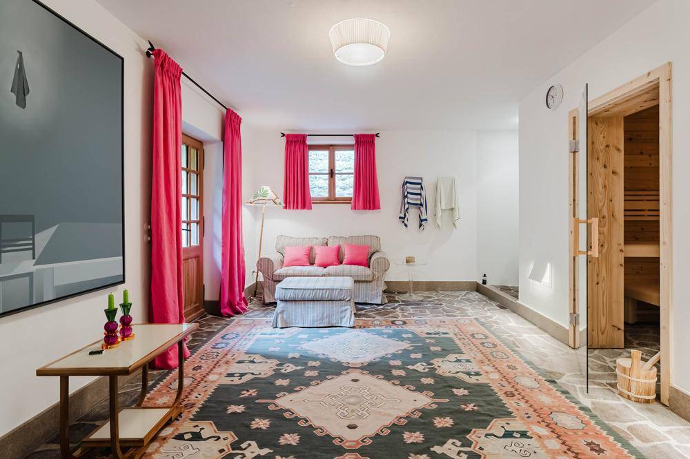 Entspannungsbereich mit Sauna, gemütlicher Sitzecke und farbenfrohem Teppich, ideal für Wellness.