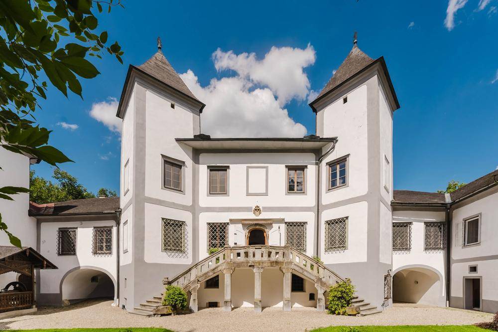 Beeindruckende Hauptfassade des historischen Anwesens mit zwei markanten Türmen und einer geschwungenen Freitreppe.