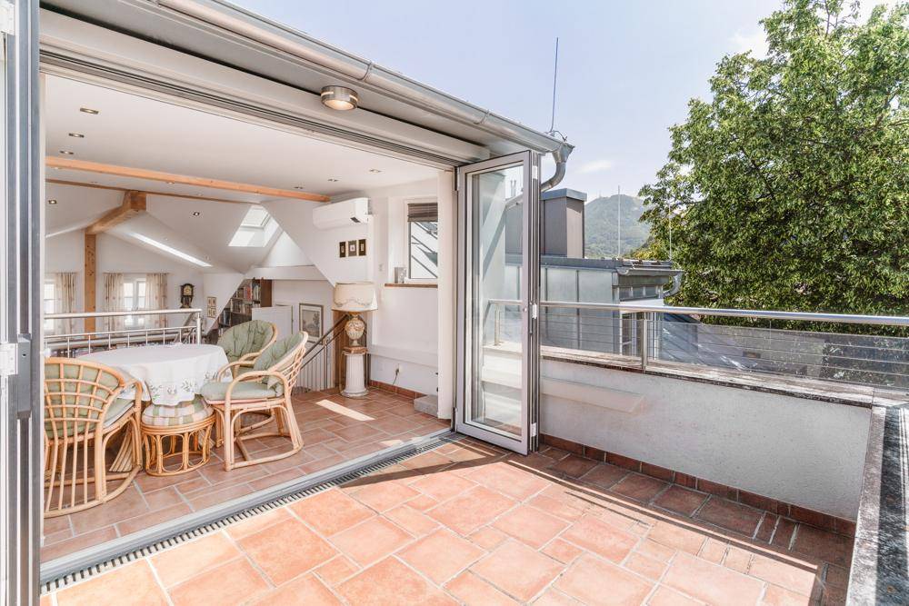 Geräumige Terrasse mit Terrakottafliesen und Rattanmöbeln, direktem Zugang zum Innenbereich.
