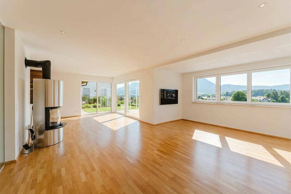Geräumiges Wohnzimmer mit Holzboden, modernem Kamin und weitem Blick auf die Berge.