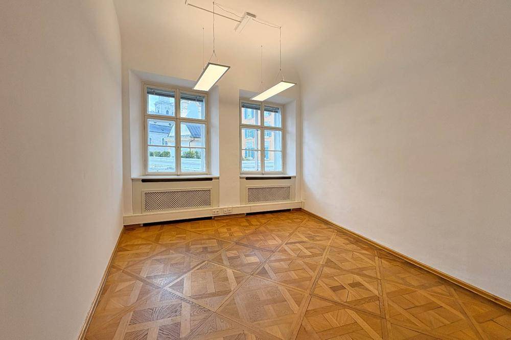 Helles Zimmer mit einzigartigem Parkettboden und zwei großen Fenstern.