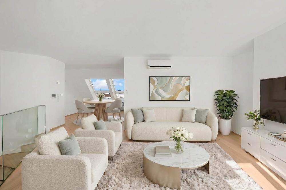 Helles, modern eingerichtetes Wohn- und Esszimmer mit Dachschrägen und stilvollen Möbeln.
