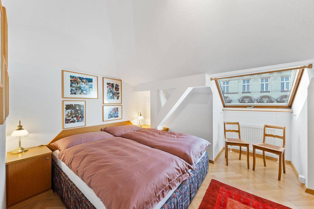 Gemütliches Schlafzimmer mit Dachschräge, Doppelbett und einem großen Dachfenster.