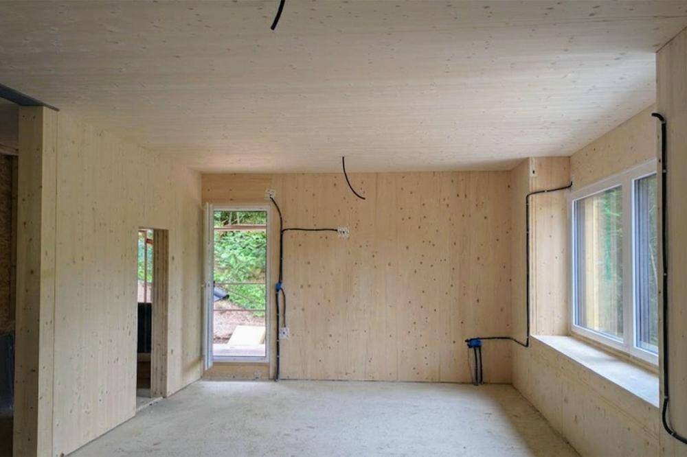 Unfertiger Raum mit Holzwänden, Betonboden und sichtbaren Elektroinstallationen, bereit für den Ausbau.