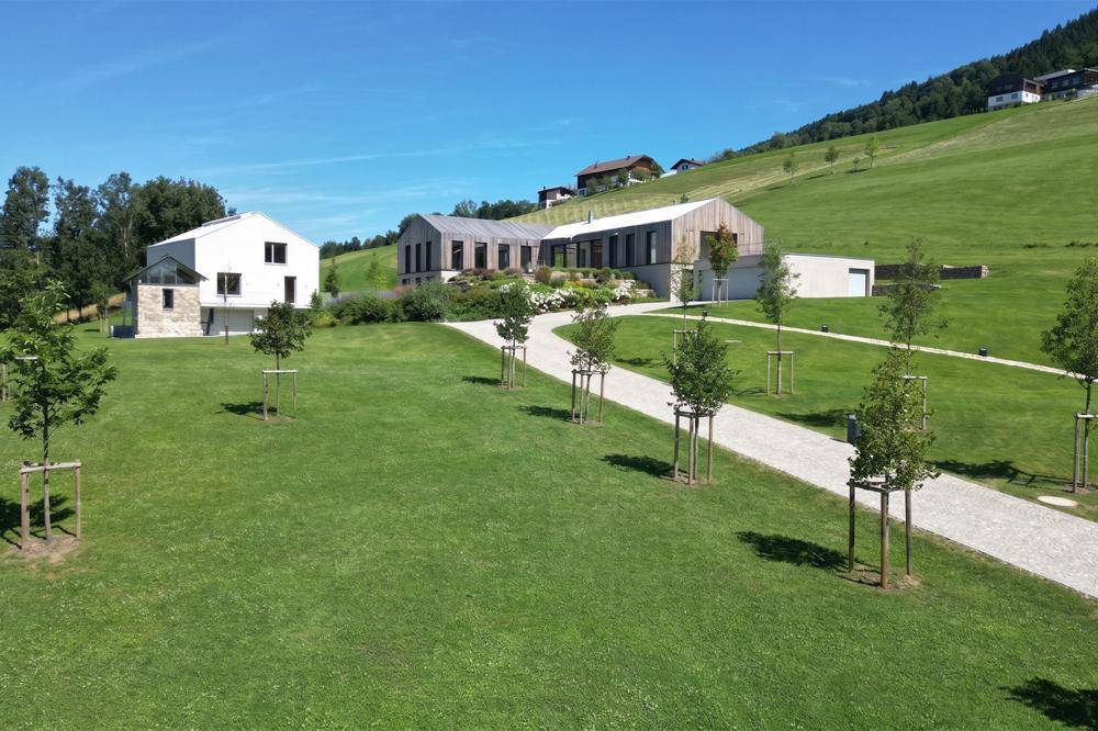 Zufahrt zur modernen Immobilienanlage mit gepflegtem Rasen und jungen Bäumen in ländlicher Umgebung.