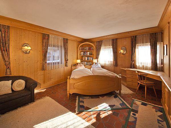 Schlafzimmer im alpinen Stil mit Holzvertäfelung, Doppelbett und Terrakottafliesen.
