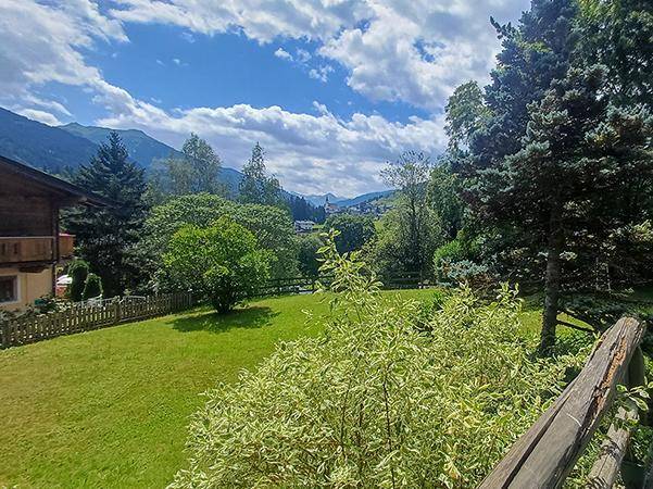 Weitläufiger grüner Garten mit Rasenfläche und Panoramablick auf die umliegende Berglandschaft.