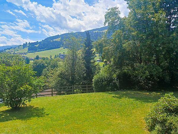 Sonniger, weitläufiger Rasenbereich mit Blick auf sanfte Hügel und grüne Natur.