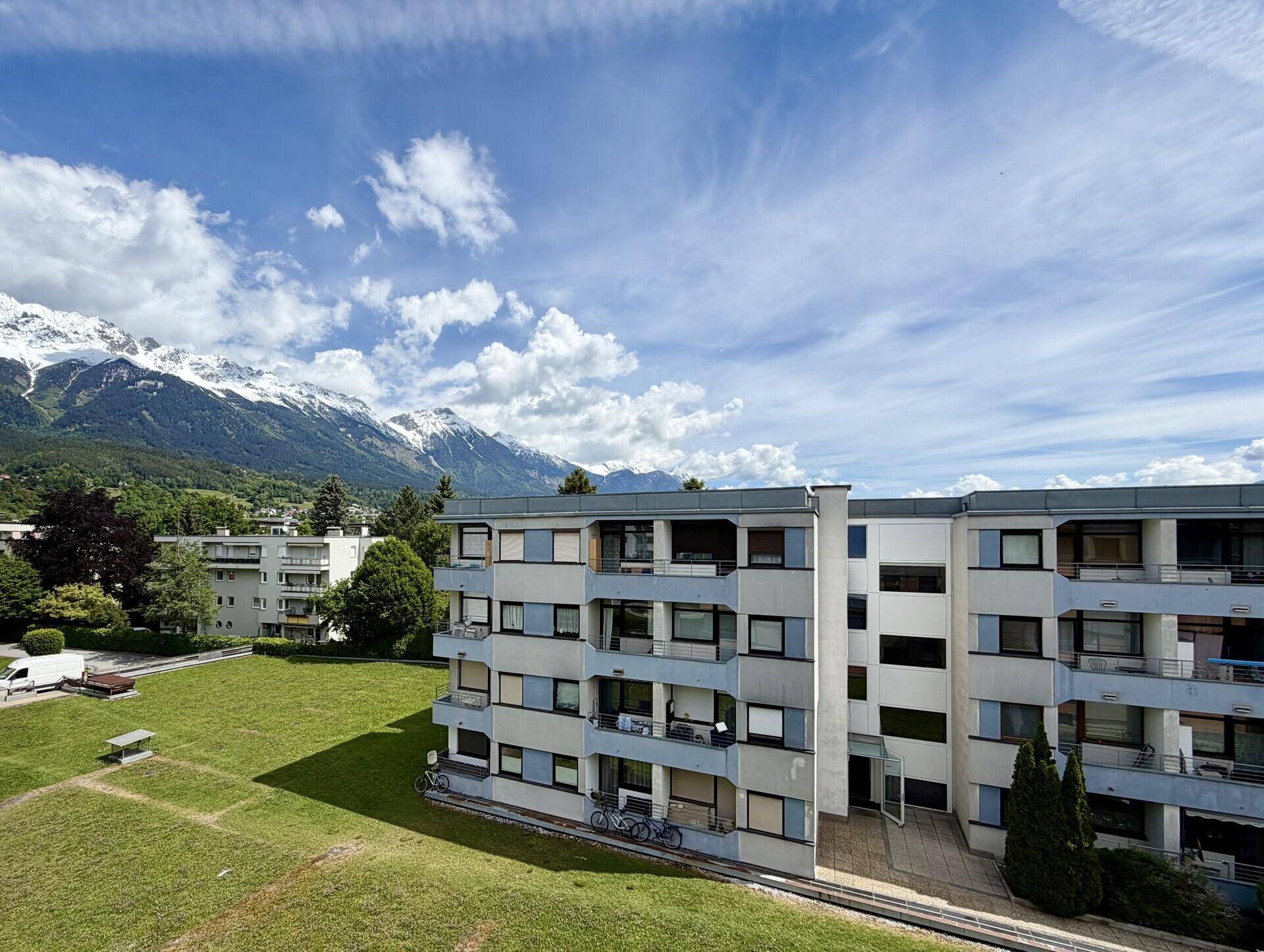 Wohngebäude mit grüner Umgebung und Panoramablick auf die umliegende Berglandschaft.