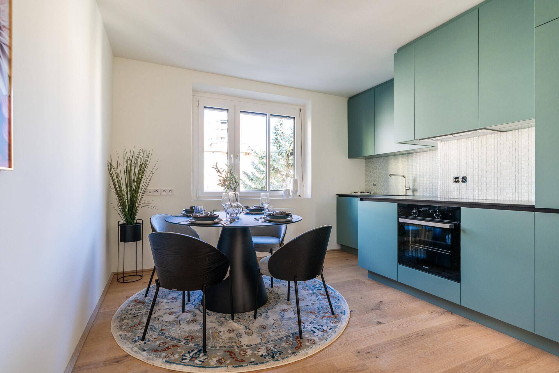 Moderne Küche mit mintgrünen Schränken, Esstisch und Holzboden.