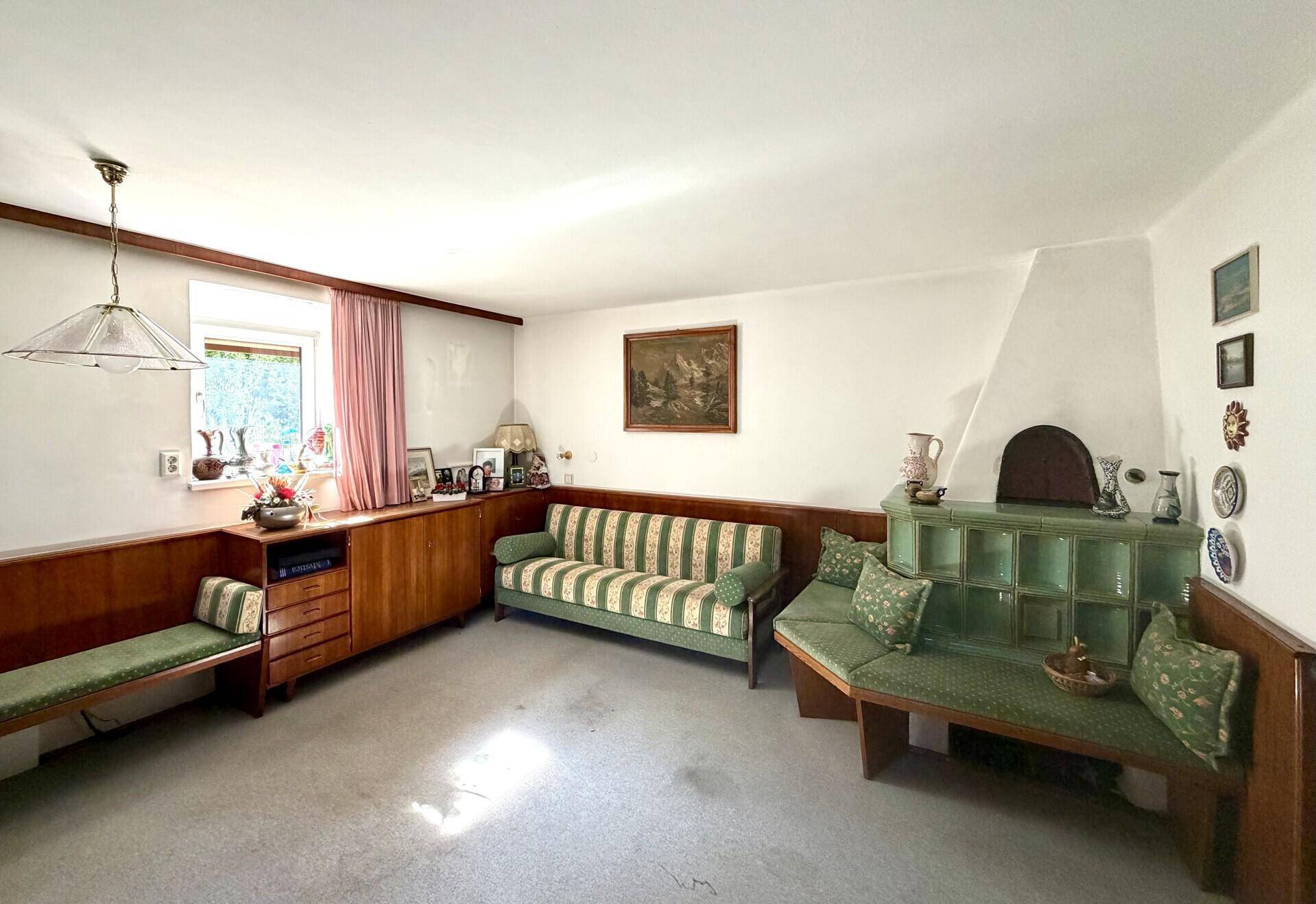 Gemütliches Wohnzimmer im traditionellen Stil mit Kachelofen, Holzvertäfelung und gestreiften Sofas.