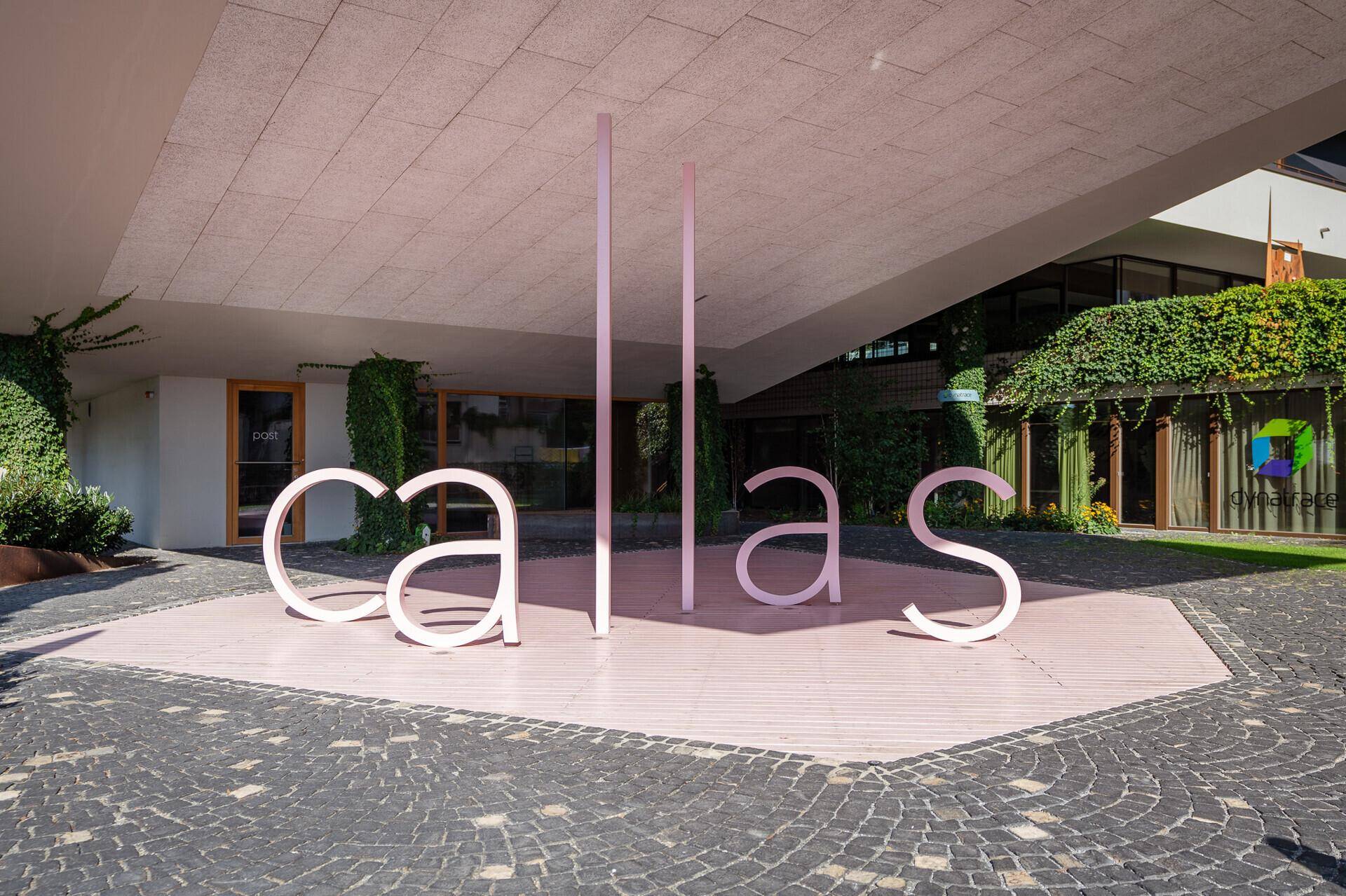Eingangsbereich des Gebäudes mit markanter "callas"-Beschriftung und gepflegter Bepflanzung.