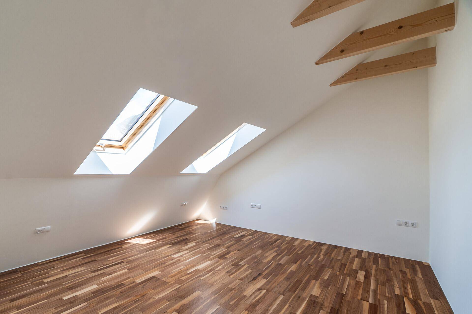 Gemütliche Ecke im Dachgeschoss mit Parkettboden und zwei Dachfenstern für natürliches Licht.