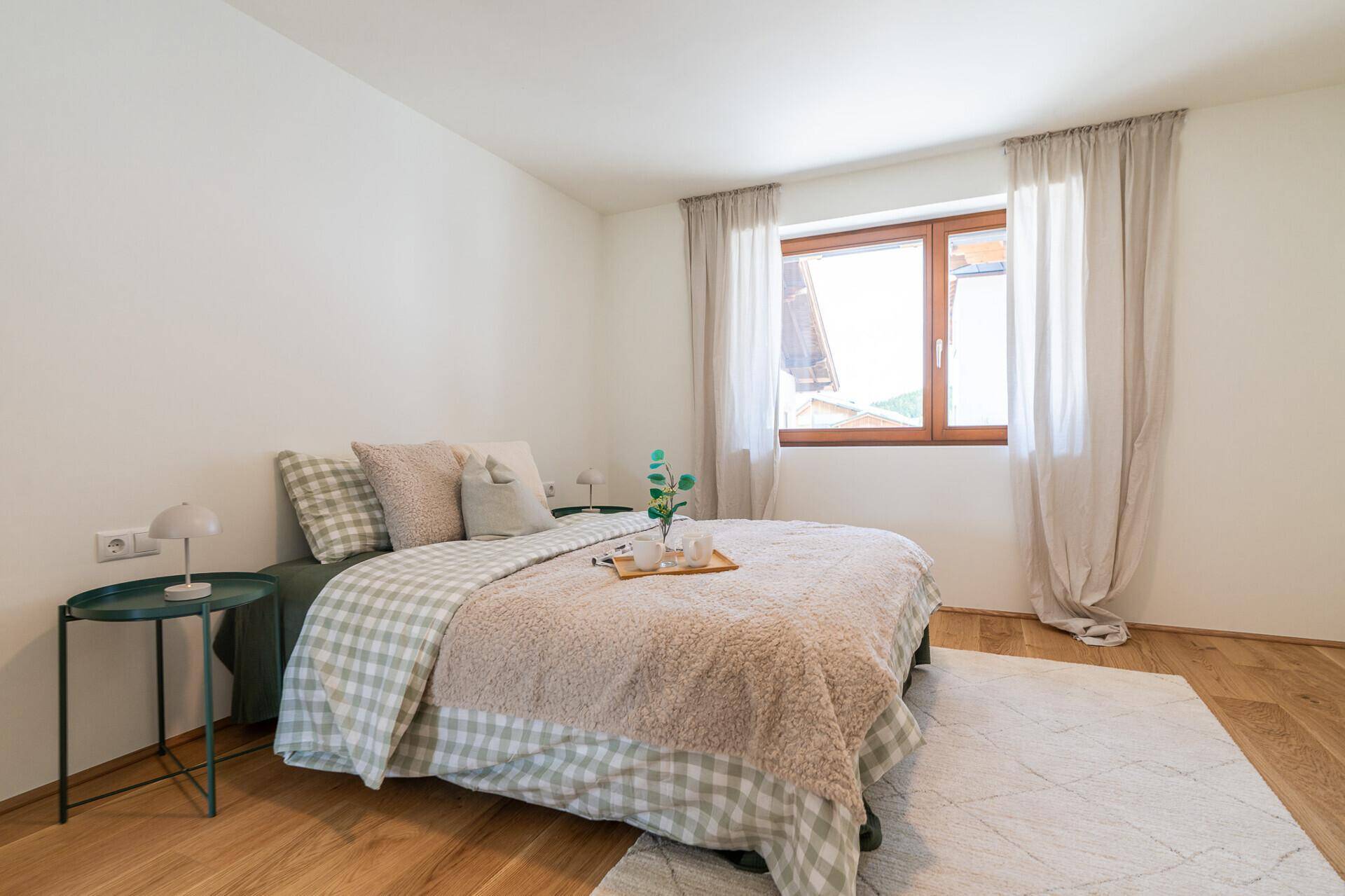 Gemütliches Schlafzimmer mit Holzboden, großem Fenster und einfacher, aber stilvoller Einrichtung.