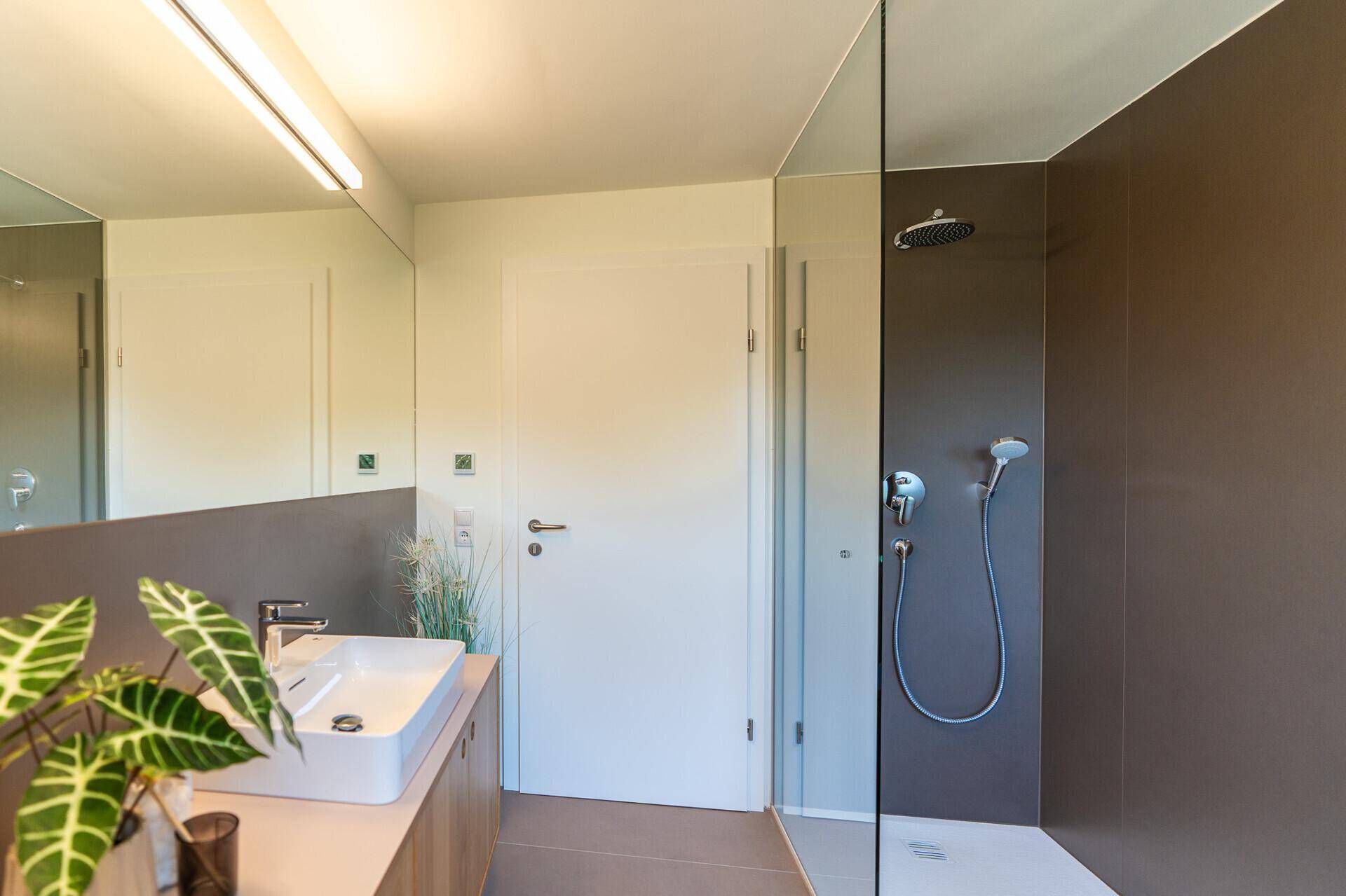 Modernes Badezimmer mit ebenerdiger Dusche, großem Spiegel und stilvollem Waschtisch.