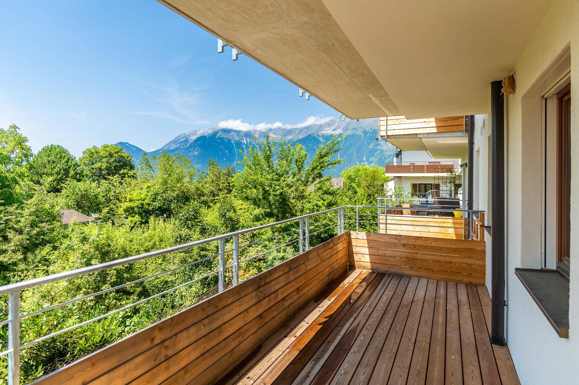 Geräumiger Holzbalkon mit Bergblick und viel Grün in der Umgebung.