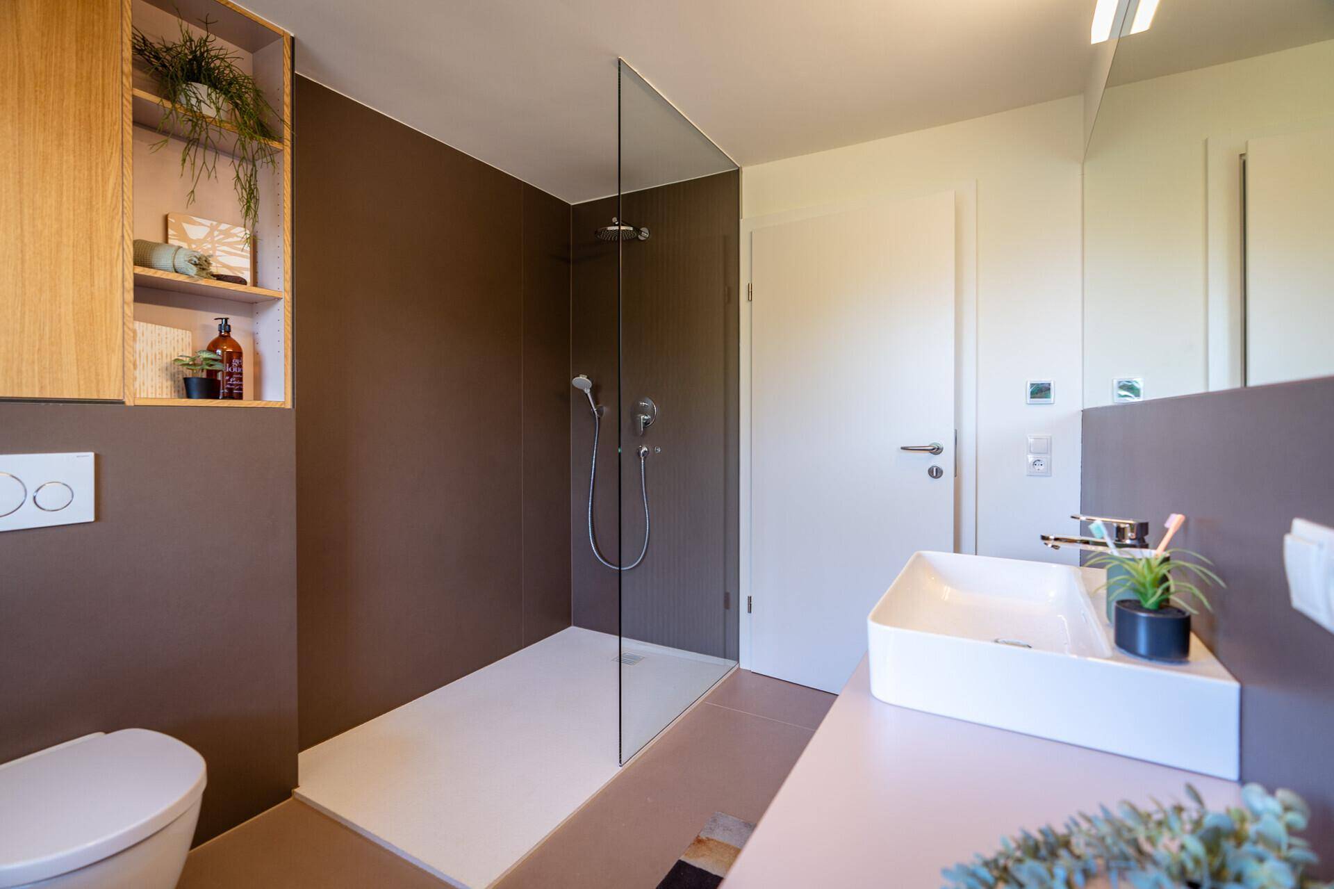 Modernes Badezimmer mit begehbarer Dusche, Wand-WC und stilvollem Waschbecken.