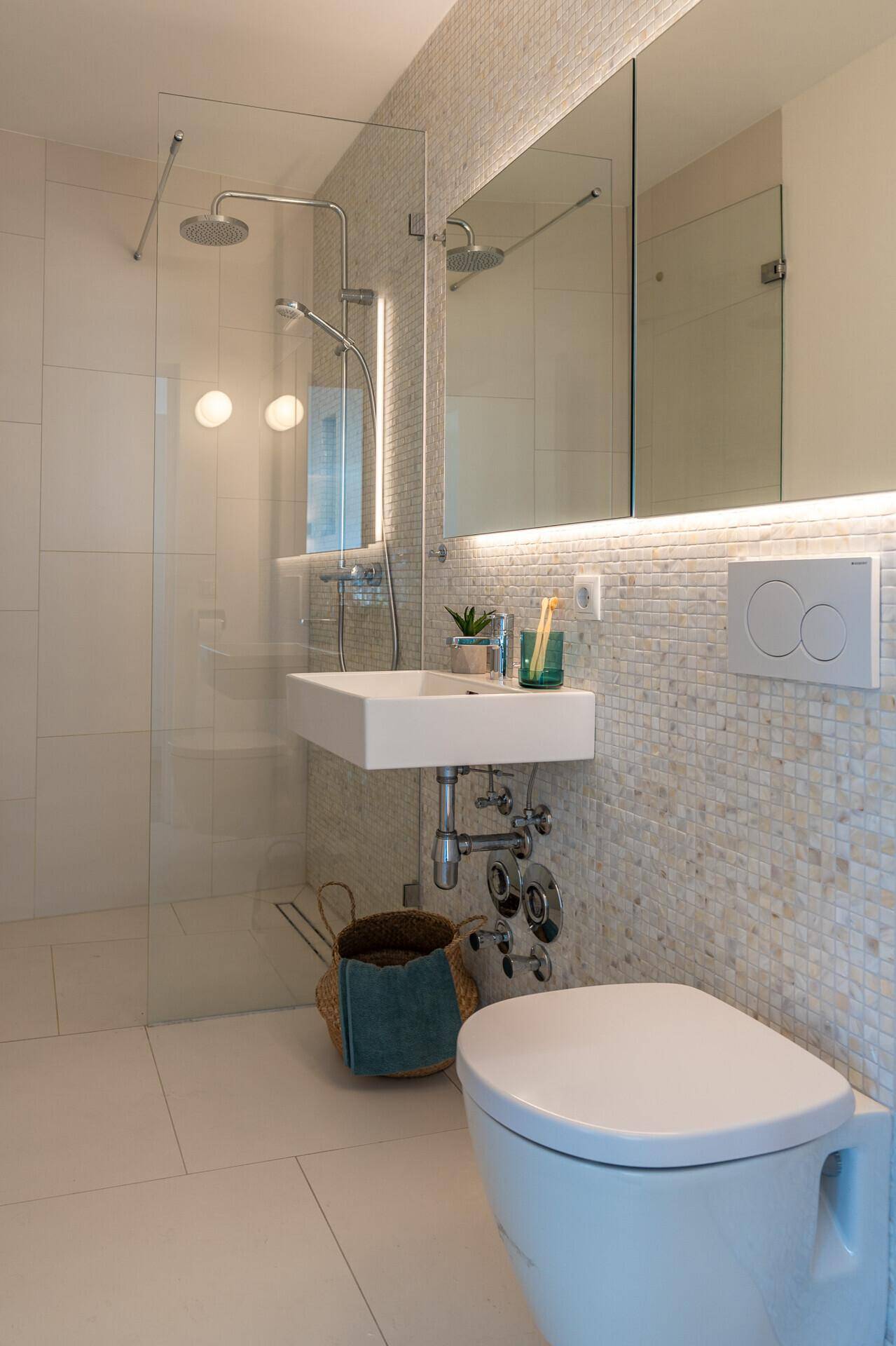 Modernes Badezimmer mit begehbarer Dusche, Hänge-WC und stilvollen Mosaikfliesen.