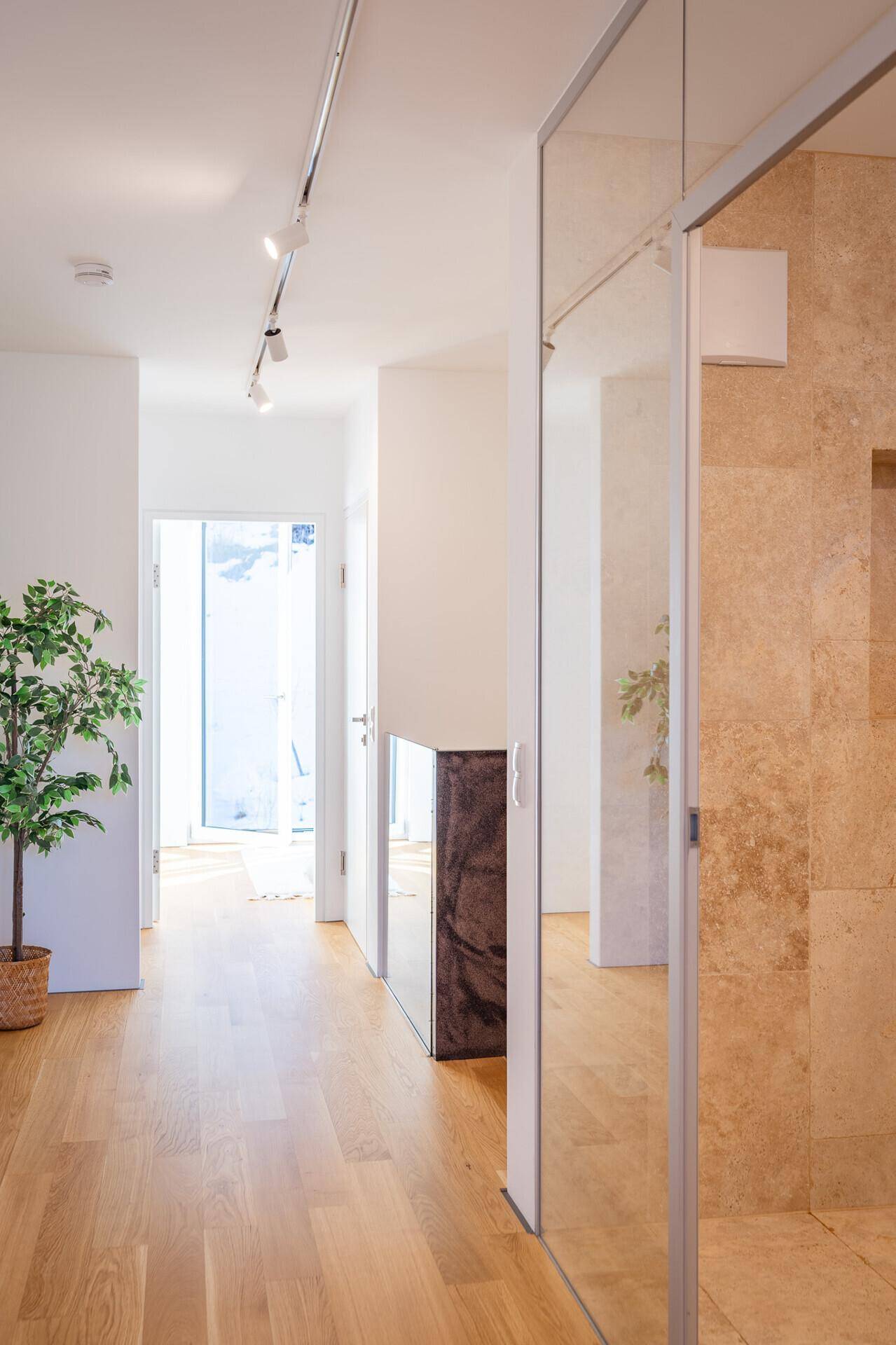 Heller Flur mit Holzboden und Zugang zu weiteren Räumen, inklusive Badezimmer.