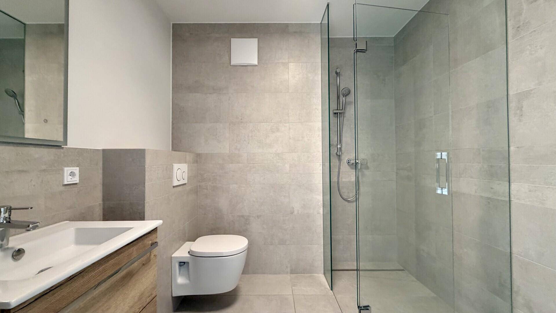 Modernes Badezimmer mit begehbarer Dusche, Wand-WC und eleganten grauen Fliesen.