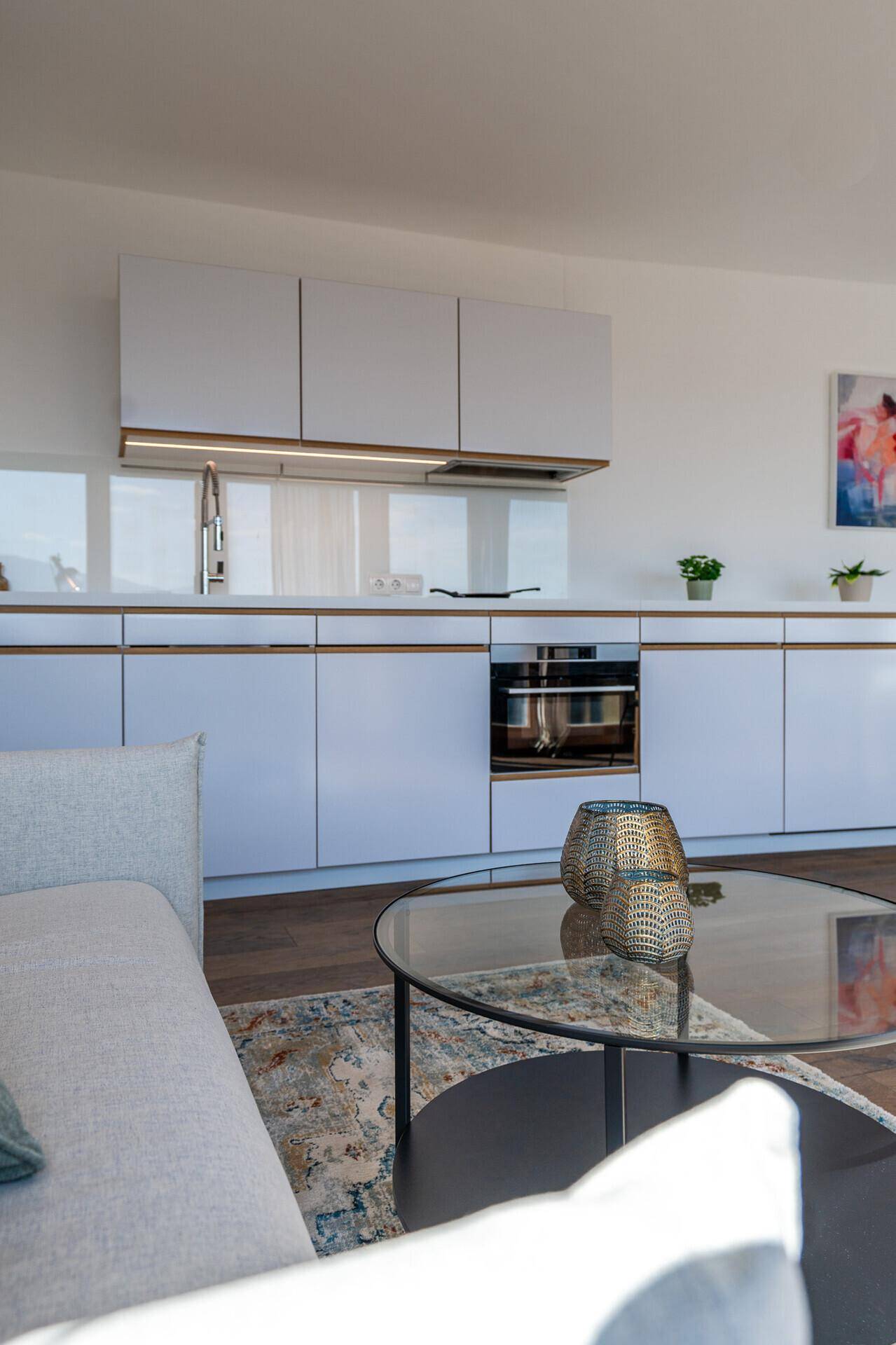 Moderne Einbauküche mit weißen Fronten, integriertem Backofen und stilvoller Beleuchtung.