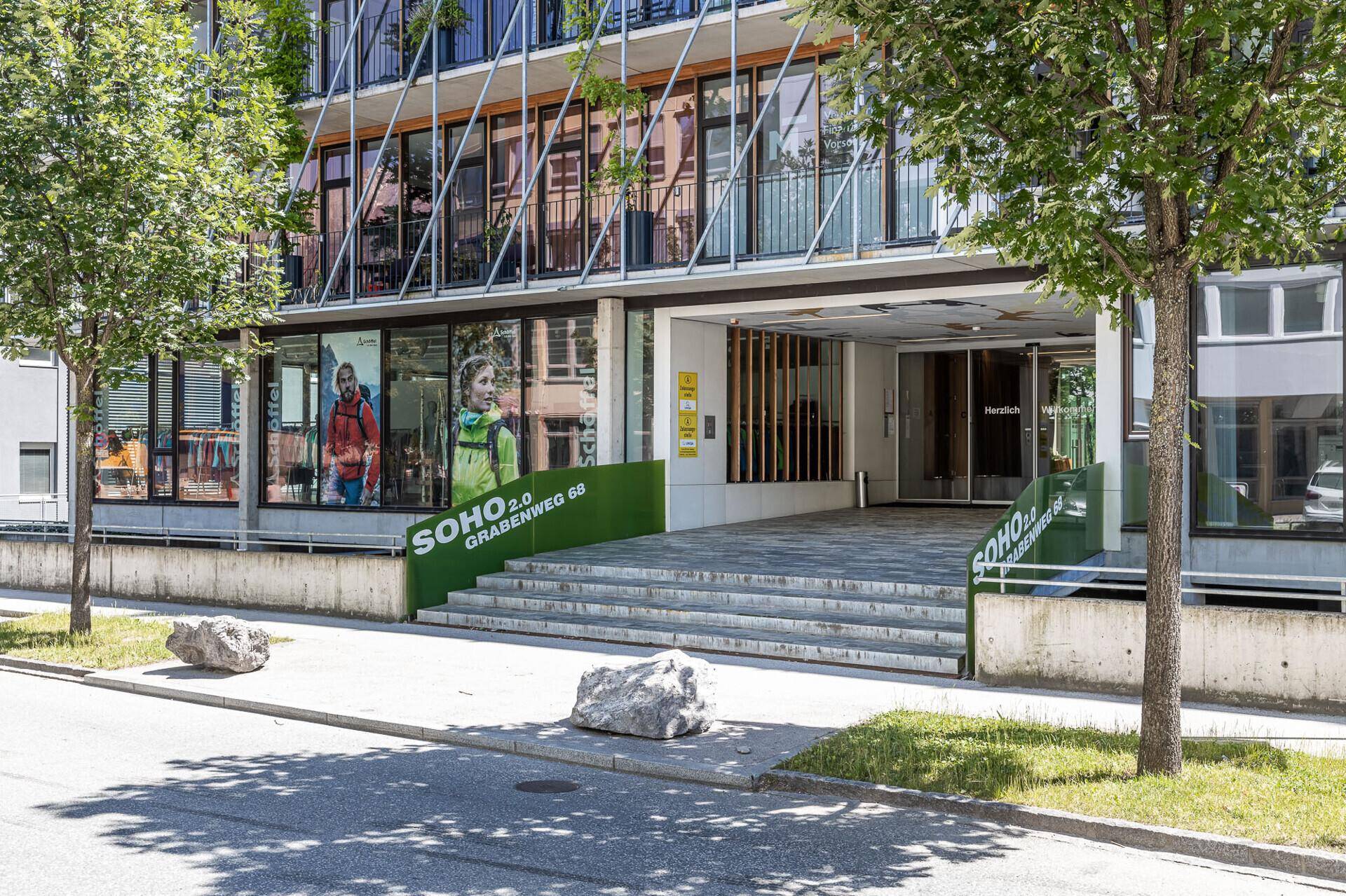 Haupteingang des modernen Bürogebäudes mit Treppen und Glasfassade.