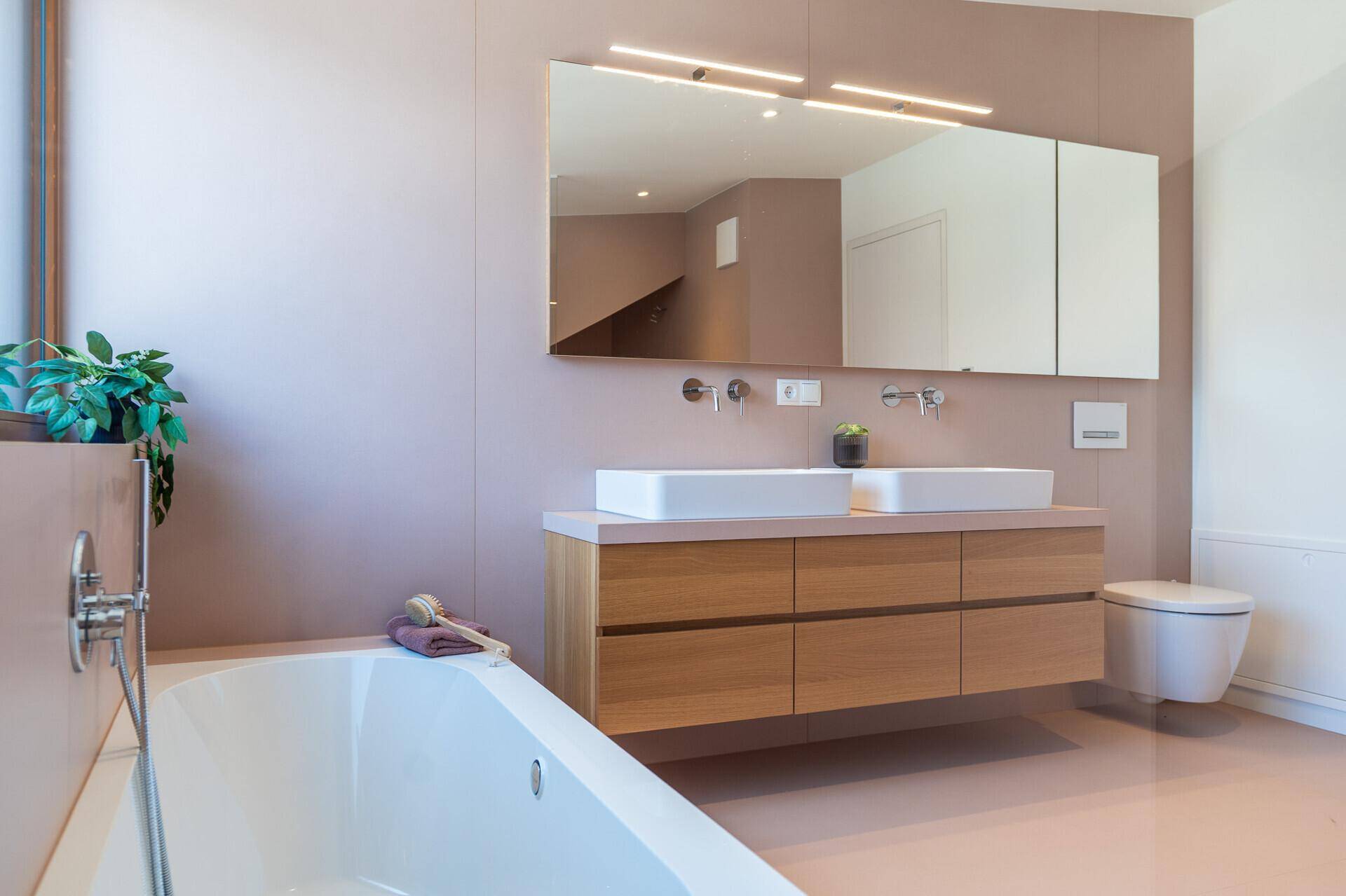 Modernes Badezimmer mit Badewanne, Doppelwaschbecken und schwebendem Holzunterschrank.