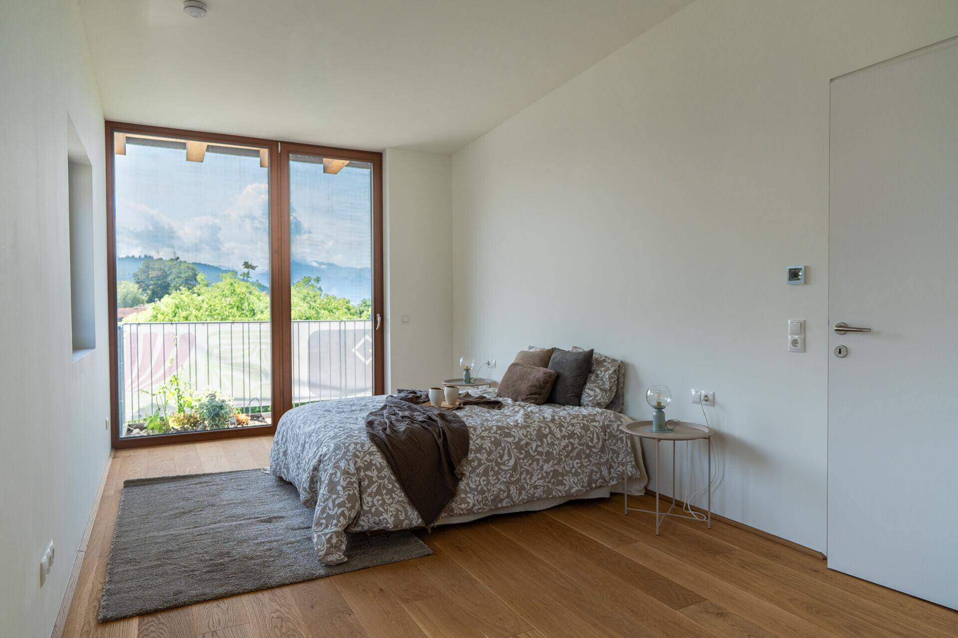 Helles Schlafzimmer mit Holzboden und Zugang zu einem Balkon mit Bergblick.