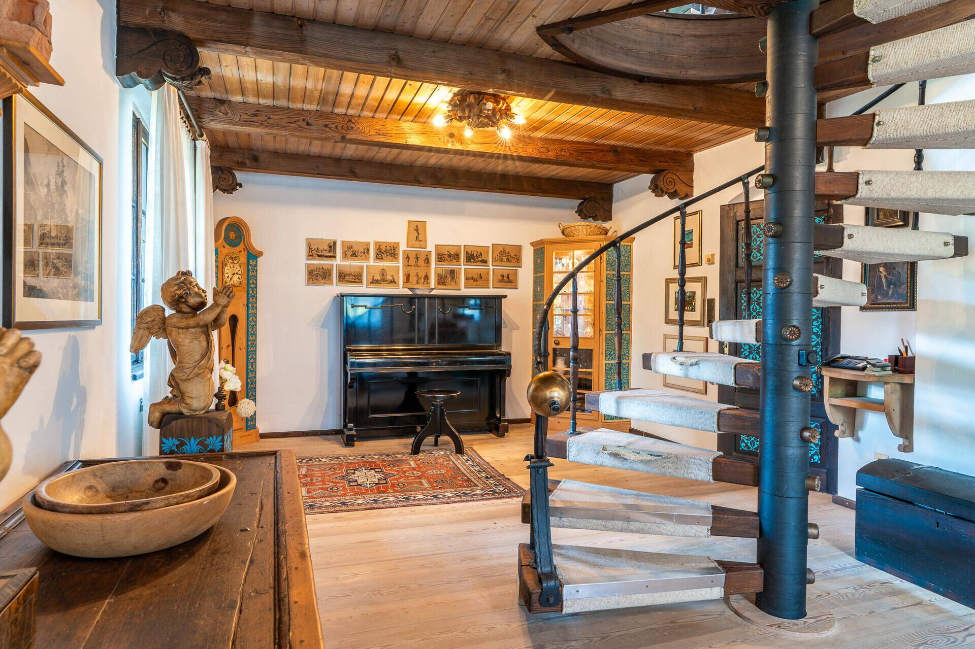 Eingangsbereich mit einer eleganten Wendeltreppe, Holzbalkendecke und traditionellen Dekorationselementen.