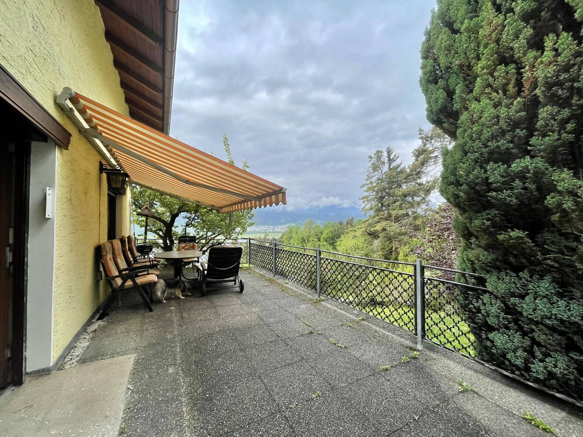 Große Terrasse mit Markise, Gartenmöbeln und weitem Blick auf die Landschaft.