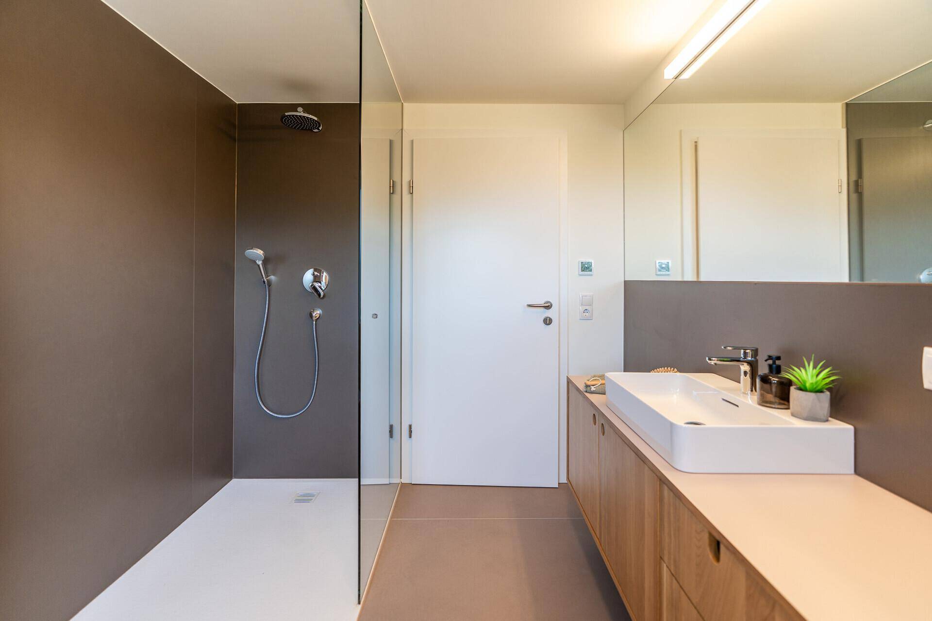 Modernes Badezimmer mit begehbarer Dusche, großem Waschbecken und Holzunterschrank.