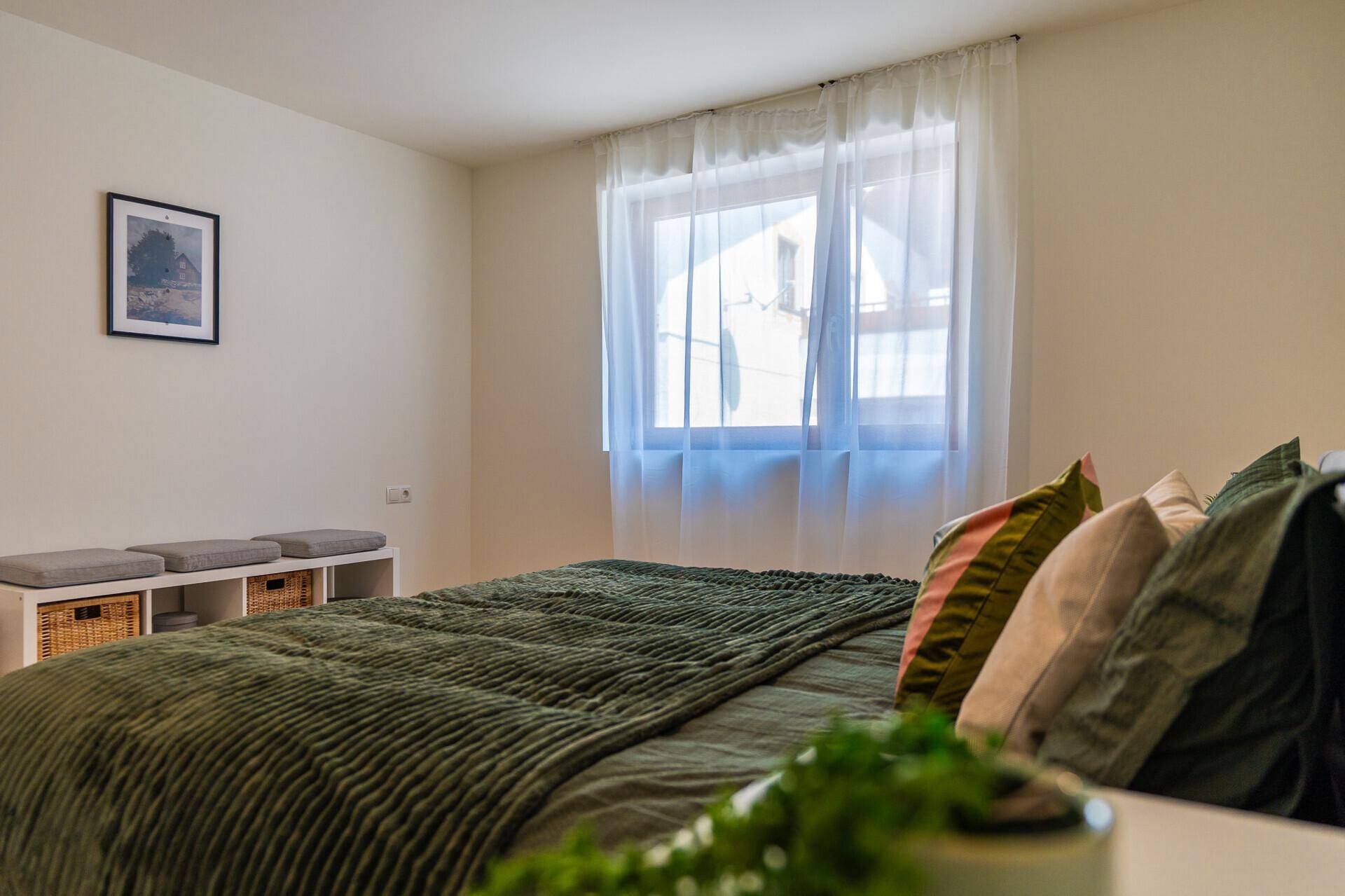 Gemütliches Schlafzimmer mit großem Bett, weichen Kissen und Fenster.