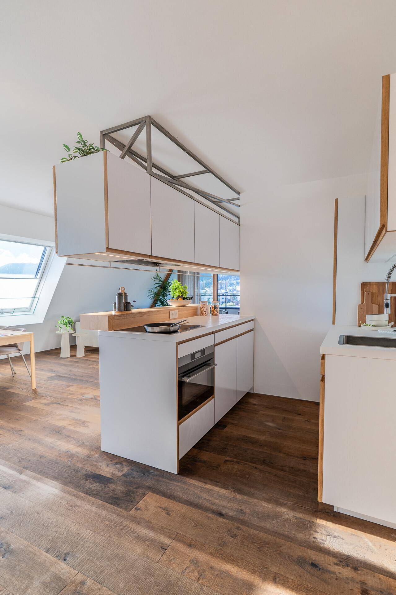 Moderne Einbauküche mit weißen Schränken, Holzarbeitsplatten und integriertem Backofen.