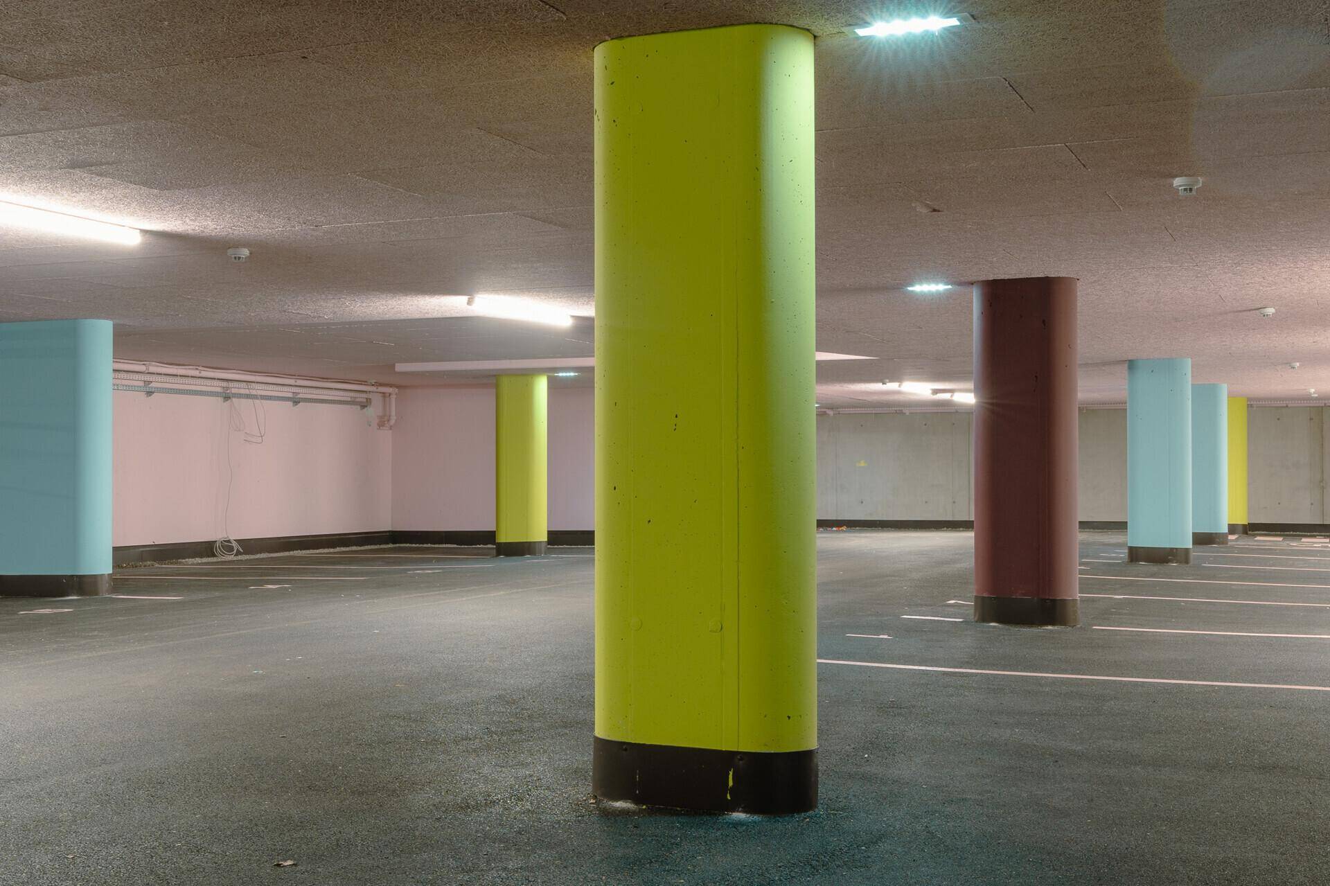 Tiefgarage mit farbigen Säulen und ausreichend Parkplätzen.