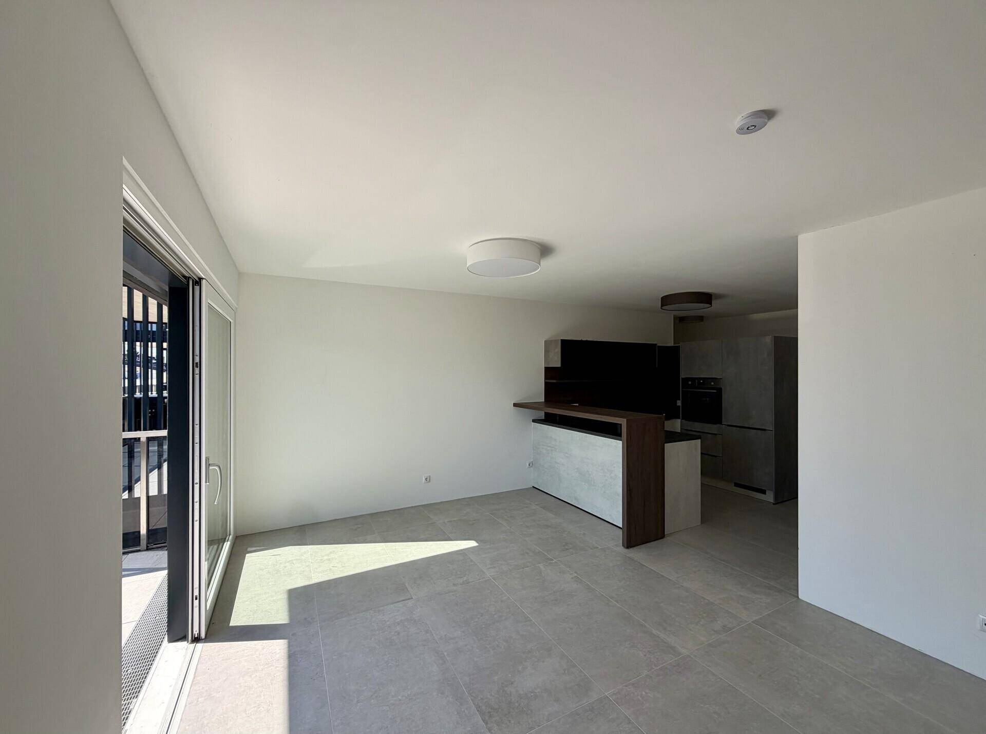 Heller, offener Wohnbereich mit modernen Fliesen und Zugang zu einem Balkon.