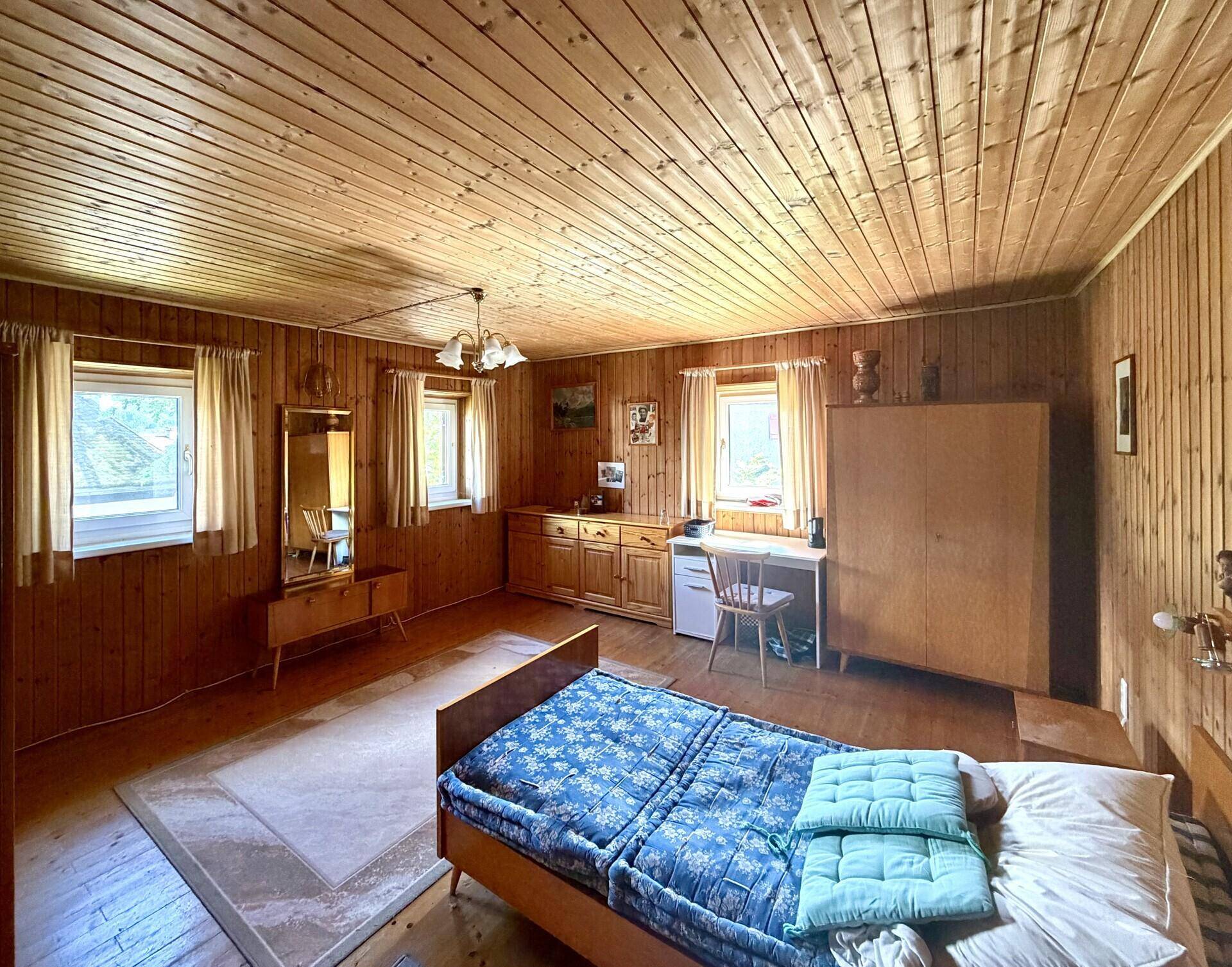Schlafzimmer im rustikalen Stil mit Holzvertäfelung an Wänden und Decke sowie Holzboden.