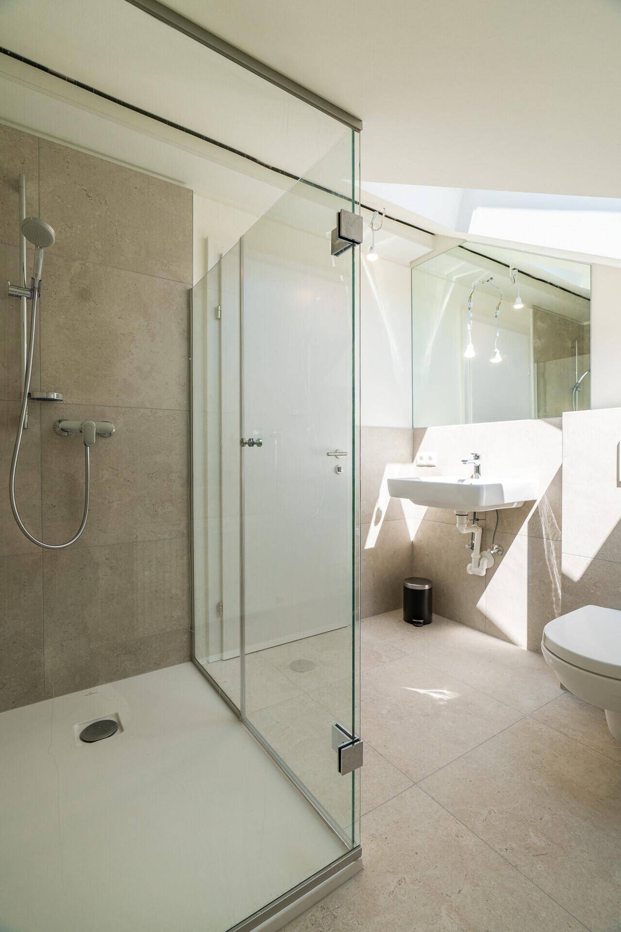 Modernes Badezimmer mit begehbarer Dusche, Wand-WC und hellem Fliesenboden.