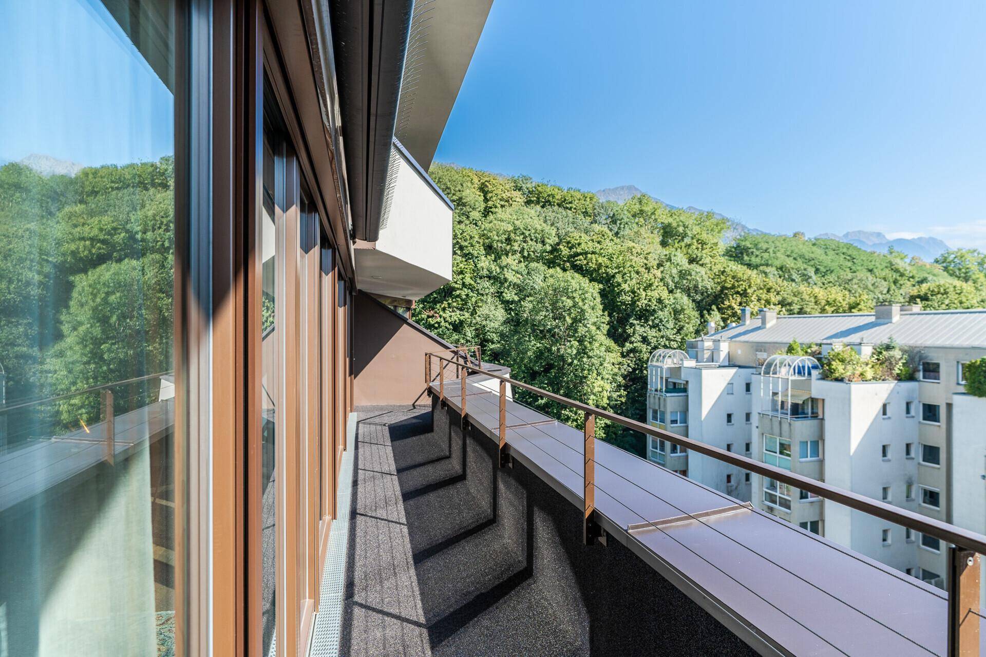 Geräumiger Balkon mit Blick auf grüne Hügel und die umliegende Wohnbebauung.