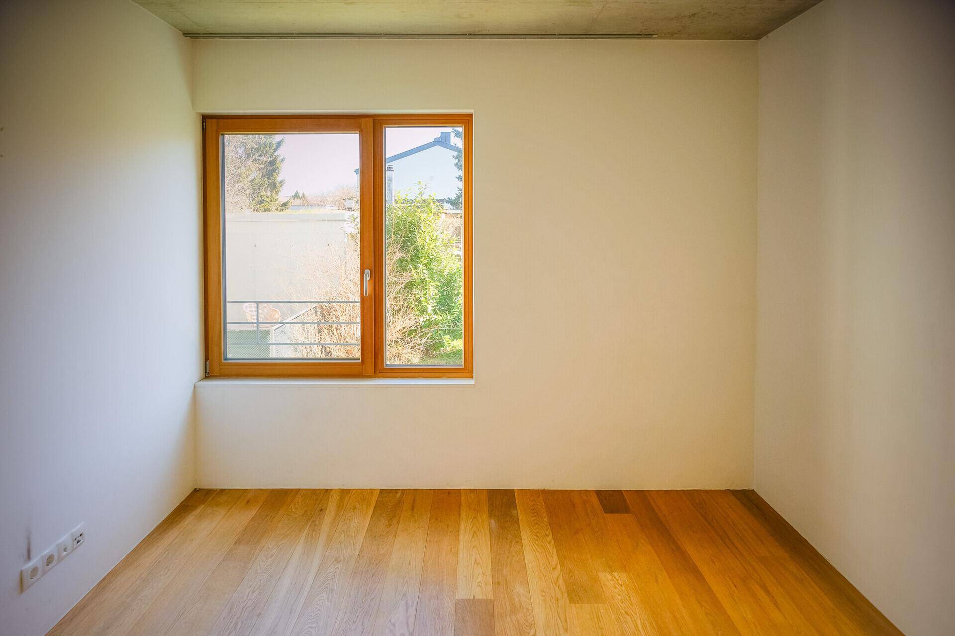 Freundliches Zimmer mit hellem Holzboden und großem Fenster, ideal als Schlaf- oder Arbeitszimmer.