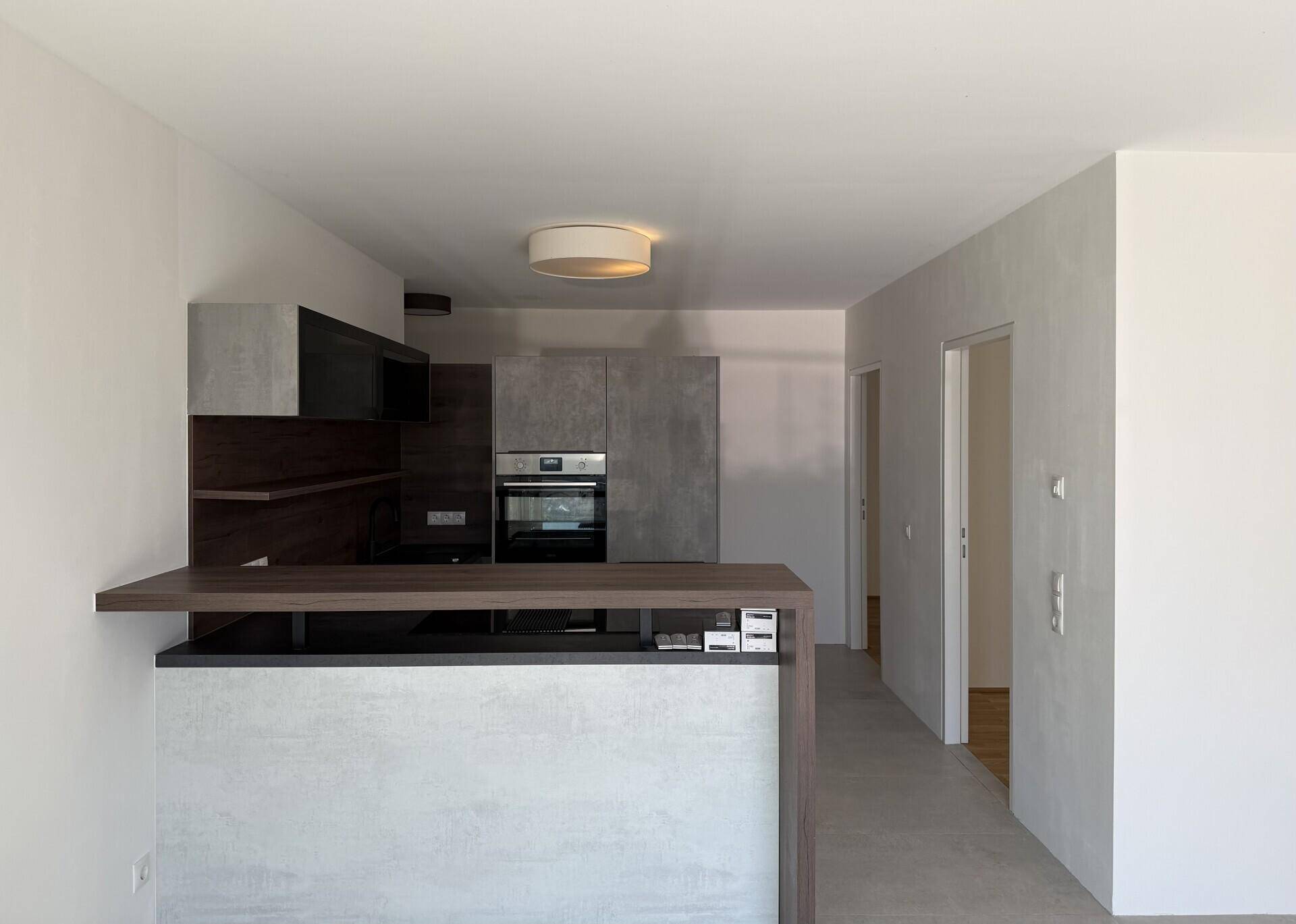Moderne Einbauküche mit grauen Fronten, Holzakzenten und integriertem Backofen.