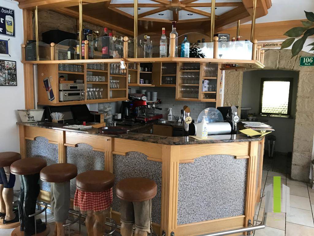Gut ausgestattete Bar mit Holztheke, Granitplatte und Hockern in traditionellem Stil.