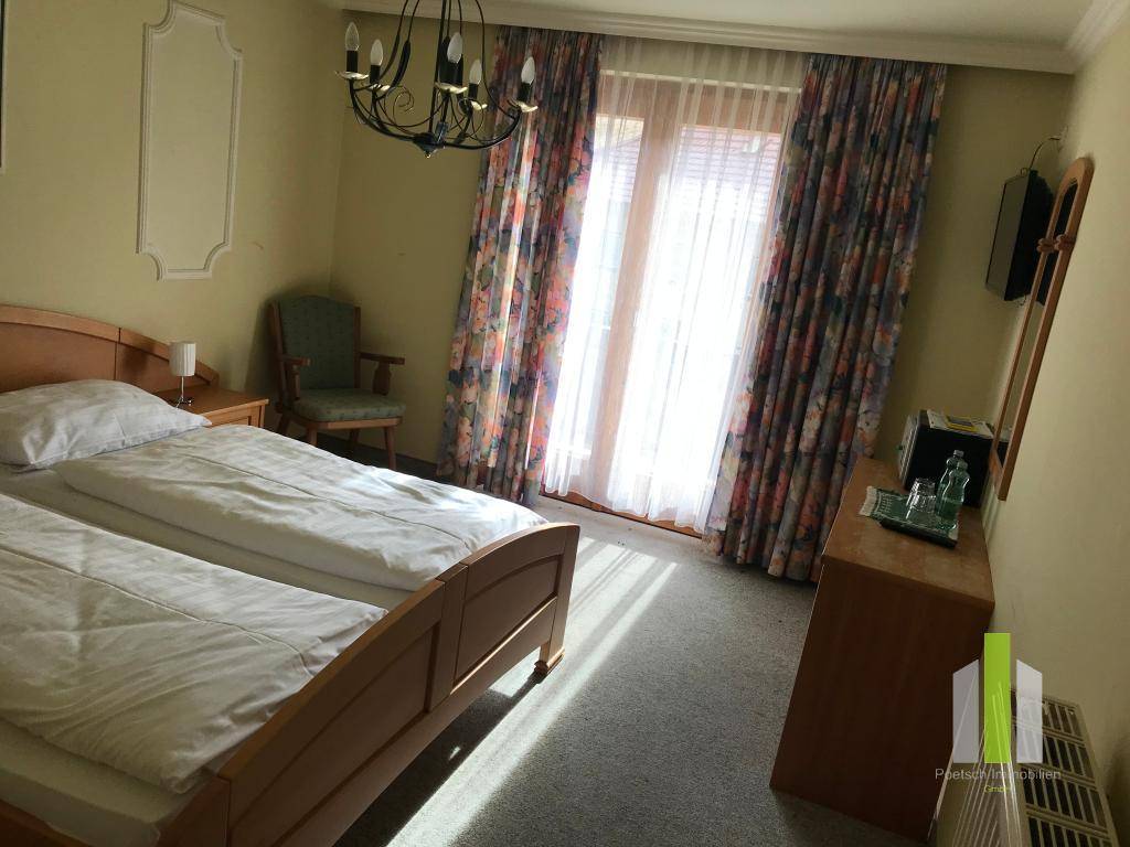 Helles Schlafzimmer mit zwei Einzelbetten, Teppichboden und Zugang zum Balkon.