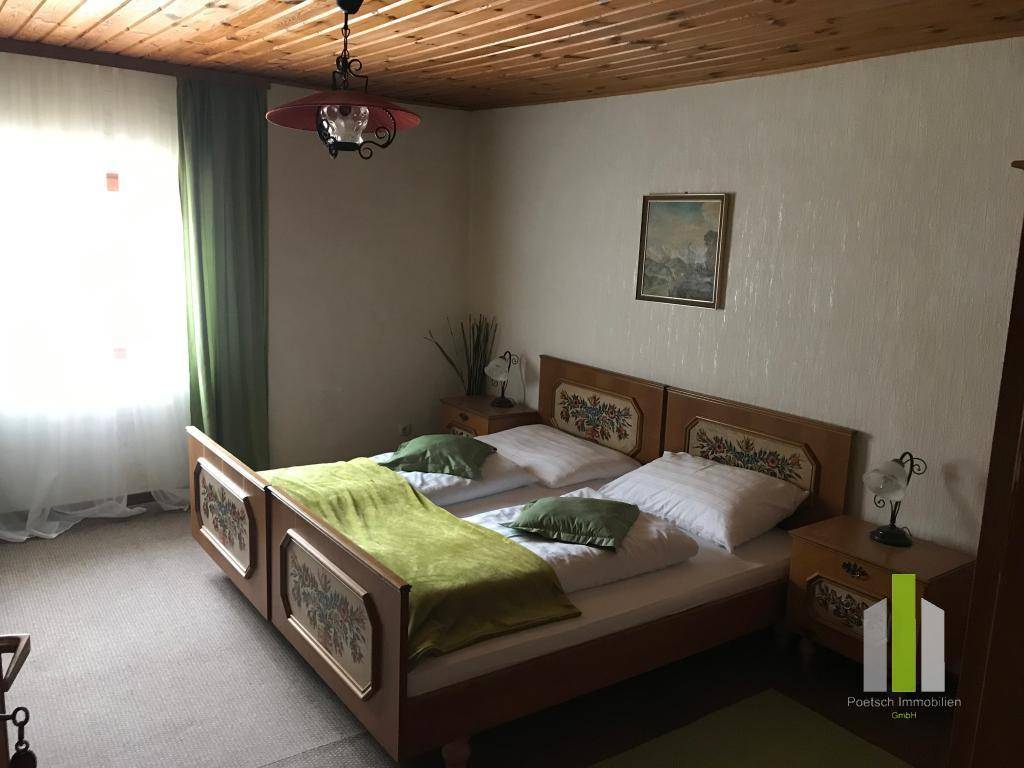 Schlafzimmer mit Holzdecke, zwei Einzelbetten und Teppichboden.