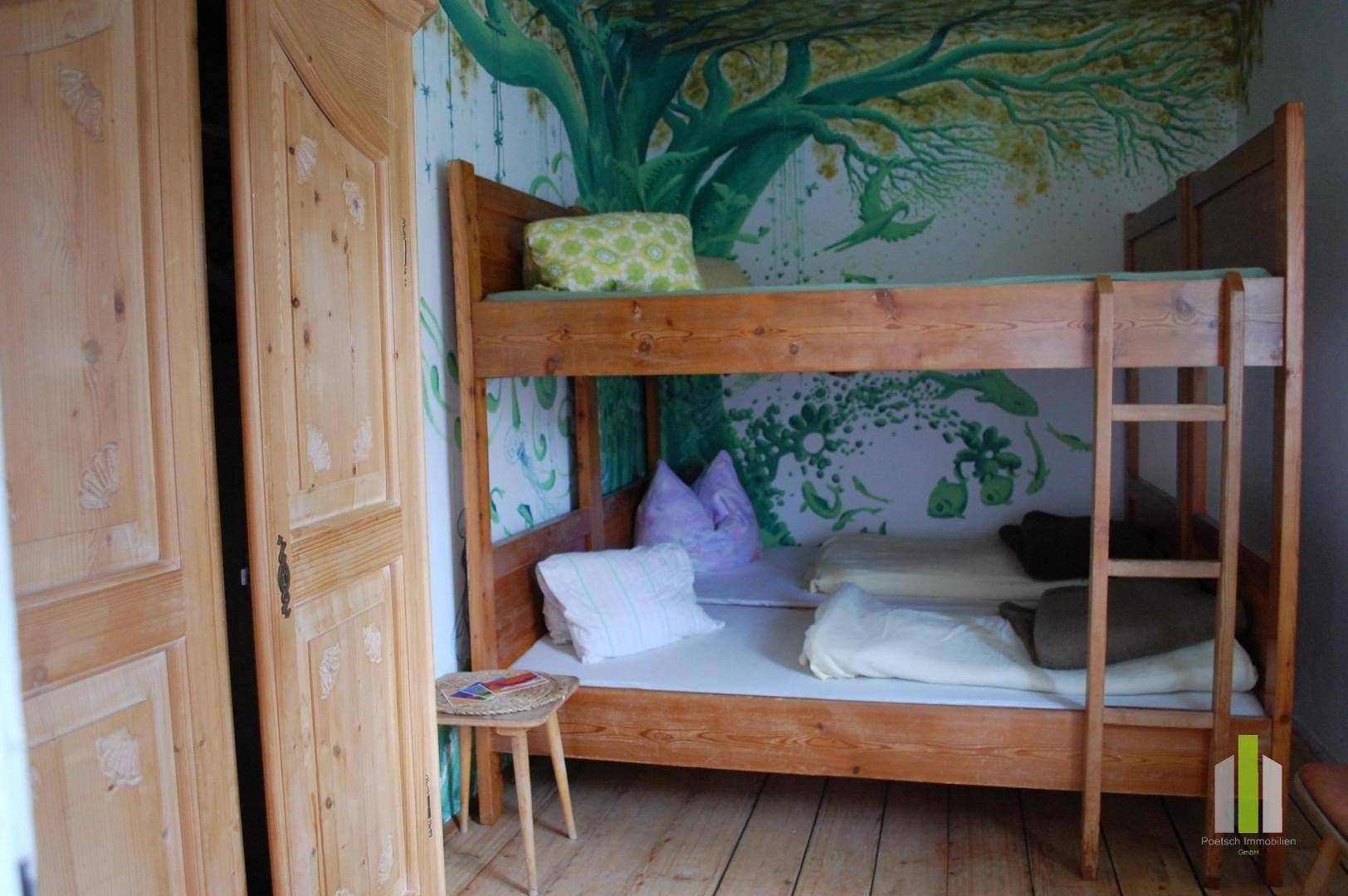 Kinderzimmer mit Etagenbett aus Holz und einer farbenfrohen Baumwandmalerei.
